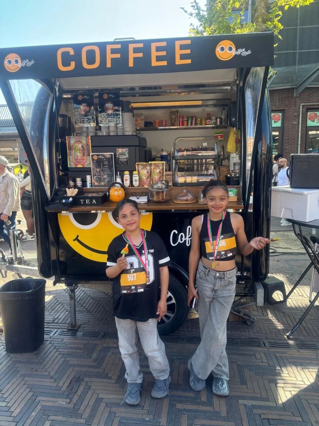 Twee meiden met medailles bij de truck na een hardloopevent